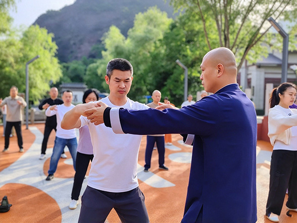 Master Shen Jiangfei correcting a student's posture by hand during an outdoor class. Master Shen Jiangfei correcting a student's posture by hand during an outdoor class.